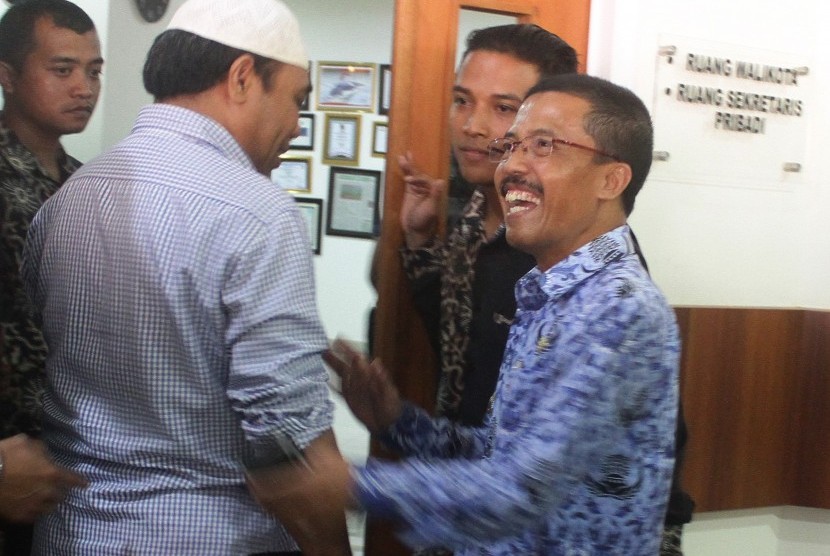 Wakil Walikota Batu Punjul Santosa (kanan) berbincang dengan tim Komisi Pemberantasan Korupsi (KPK) sebelum melakukan penggeledahan di depan ruang Walikota Batu di Balaikota Amongtani, Batu, Jawa Timur, Senin (18/9).