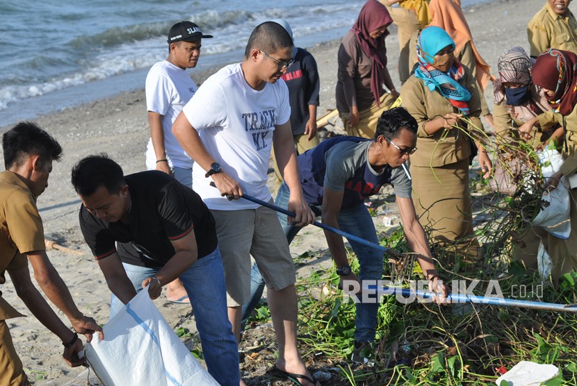 Wakil Walikota Palu, Sigit Purnomo Said atau Pasha Ungu (tengah) bergotong-royong bersama sejumlah pegawai membersihkan rerumputan dan sampah yang berserakan di Pantai Teluk Palu, Sulawesi Tengah, Selasa (20/2).