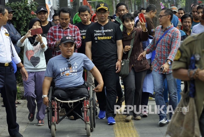 Wali Kota Bandung Ridwan Kamil berjalan menuju Pendopo didamping warga disabilitas di trotoar seusai peresmian revitalisasi Trotoar Kota Bandung di Jalan Ir.H. Djuanda (Dago), Kota Bandung, Ahad (19/2).