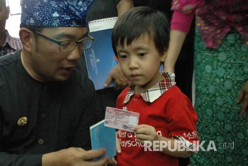 Wali Kota Bandung Ridwan Kamil bersama seorang anak memperlihatkan Kartu Identitas Anak (KTA) pada 