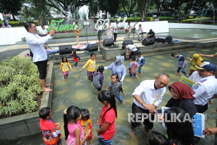 Wali Kota Bandung Ridwan Kamil (kiri) memotret warga yang bermain di kolam dangkal di Taman Badak, Kota Bandung, Selasa (19/12).