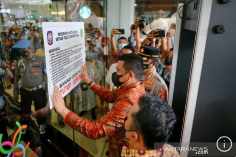 Wali Kota Medan Bobby Nasution saat menempelkan stiker penyegelan di pintu masuk Mal Center Point, Kota Medan, Sumatra Utara, Jumat (9/7/2021).