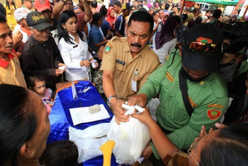 Wali Kota Solo FX Hadi Rudyatmo (tengah) membagikan bungkusan paket sembako saat pembukaan Operasi Pasar Murah di Lapangan Losari, Semanggi, Pasar Kliwon, Solo, Jawa Tengah, Kamis (9/7).