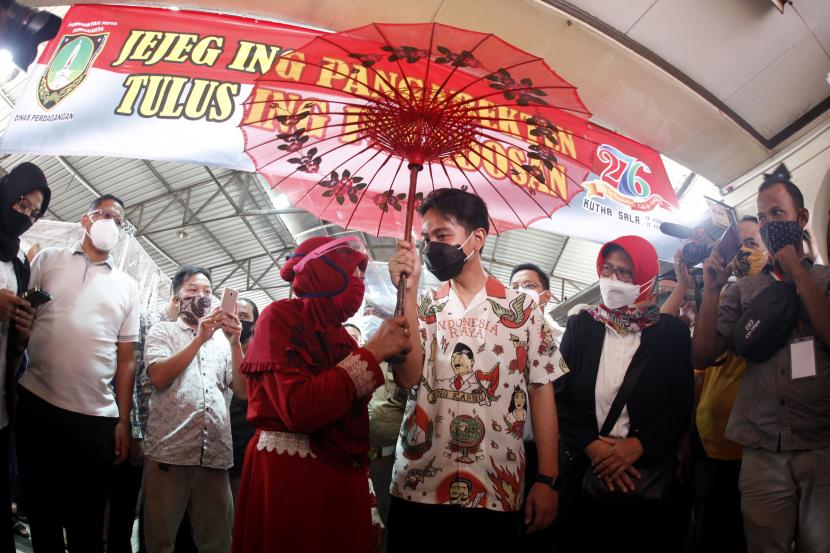 Wali Kota Solo Gibran Rakabuming Raka (tengah) menerima payung dari warga saat mengunjungi Pasar Gede seusai pelantikan di Solo, Jawa Tengah, Jumat (26/2/2021). Gibran Rakabuming Raka dan Teguh Prakosa resmi dilantik menjadi Wali Kota dan Wakil Wali Kota Solo periode 2021-2026.
