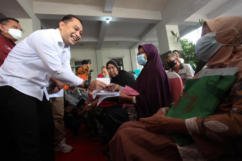 Wali Kota Surabaya Eri Cahyadi (kiri) menyalurkan Bantuan Langsung Tunai (BLT) minyak goreng kepada warga di kantor Kecamatan Rungkut, Surabaya, Jawa Timur, Sabtu (16/4/2022). 
