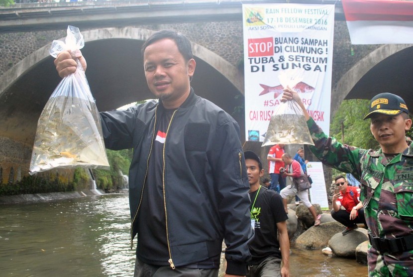 Walikota Bogor Bima Arya (kiri) menebar bibit ikan mata merah di aliran sungai Ciliwung, Kelurahan Sempur, Kota Bogor, Jawa Barat, Minggu (18/12).