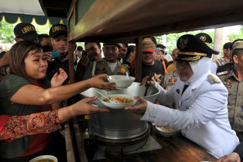 Walikota Surabaya, Tri Rismaharini (kanan) menyerahkan soto bagi masyarakat dalam pesta rakyat usai upacara hari jadi kota Surabaya (HJKS) ke-719 di Taman Surya Balai Kota Surabaya, Jatim, Kamis (31/5).