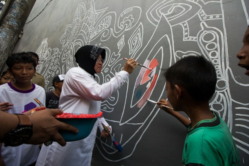 Walikota Surabaya Tri Rismaharini (kedua kanan) melukis mural bermotif batik bersama warga di kawasan Putat, Surabaya, Jawa Timur, Senin (19/12). 