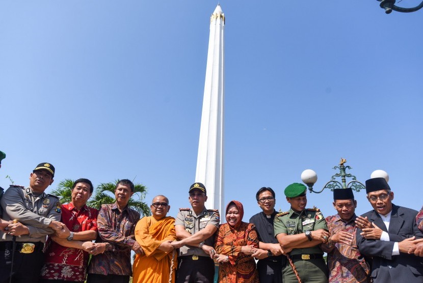  Walikota Surabaya Tri Rismaharini (tengah) bergandengan tangan dengan sejumlah pejabat kota dan perwakilan pemuka agama ketika pernyataan sikap bersama di Tugu Pahlawan, Surabaya, Jawa Timur, Jumat (24/7). 