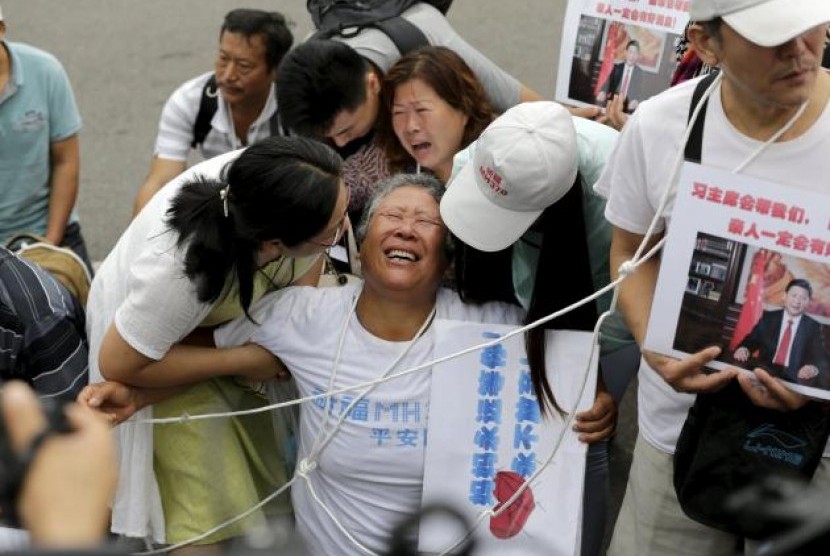 Wang Zhuncai (tengah) kehilangan putrinya dalam penerbangan MH370. Dia bergabung bersama keluarga lain yang kehilangan di dekat Kedutaan Malaysia di Beijing, Jumat (7/8).