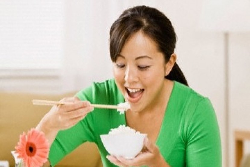 Wanita Asia sedang makan nasi.
