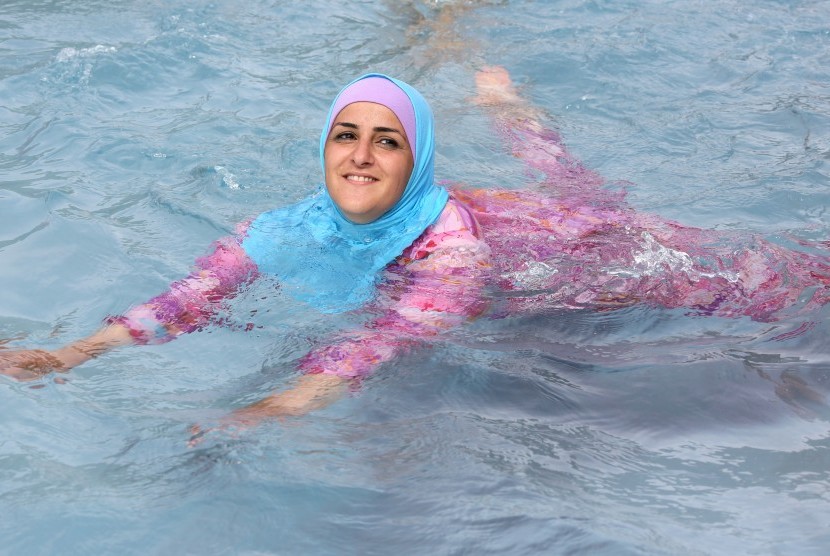 Wanita berenang menggunakan burkini.