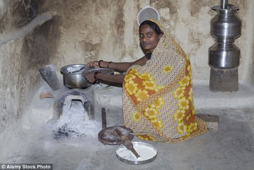 Wanita India memasak menggunakan kompor tradisional.