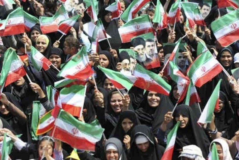 Wanita Iran mengibarkan bendera Iran.