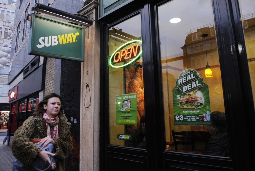 Wanita melalui salah satu gerai sandwich Subway di Inggris.