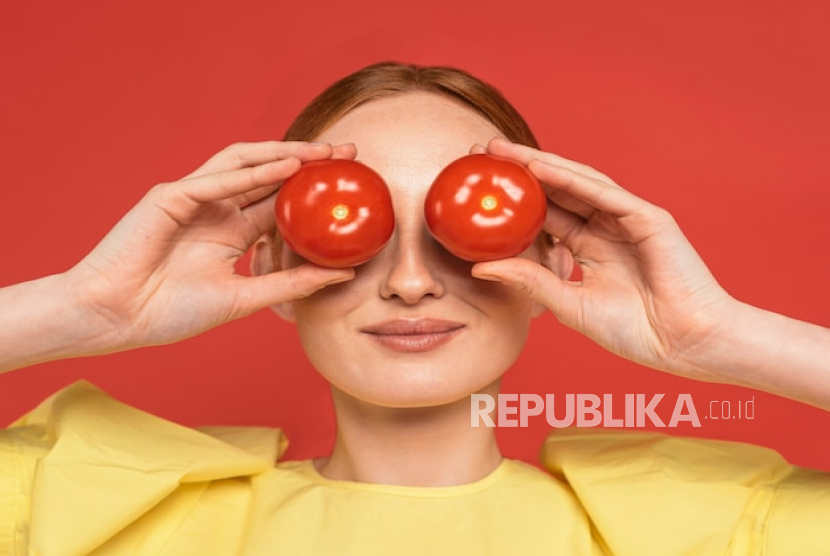 Wanita memegang tomat (ilustrasi). Hingga kini belum ada bukti ilmiah yang mendukung bahwa mengoleskan tomat langsung ke kulit dapat memberikan manfaat nyata.