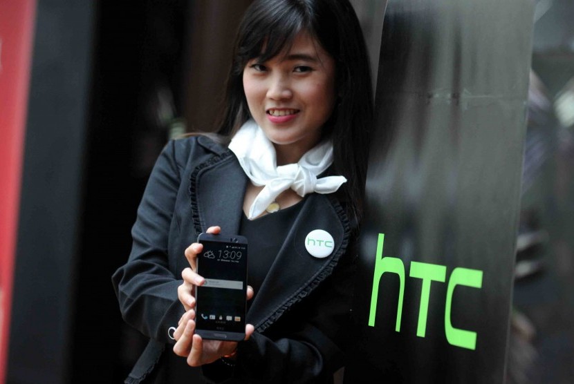 Wanita memperlihatkan ponsel HTC.