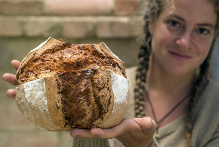 Wanita memperlihatkan roti yang baru dibuatnya.