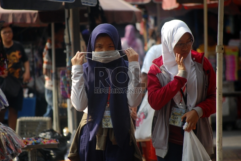 Wanita menggunakan masker untuk menghindari polusi udara.