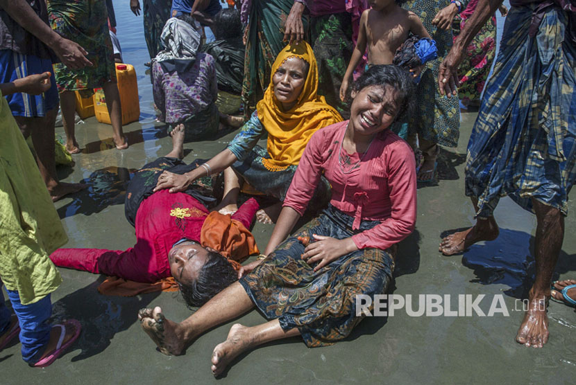 Wanita Muslim Rohingya, yang menyeberang dari Myanmar ke Bangladesh, meratap karena kerabatnya tidak sadar setelah kapal yang mereka tumpangi berbaris beberapa menit sebelum mencapai pantai di Shah Porir Dwip, Bangladesh,Kamis, (14/9).