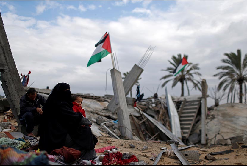 Wanita Palestina berkumpul di dekat rumahnya yang hancur di selatan Jalur Gaza, Senin (13/1). 