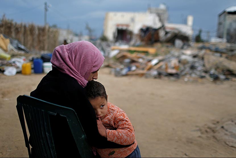 PBB: Pengungsi Palestina Butuh Bantuan Rp 1,4 Triliun. Wanita Palestina bersama anaknya di dekat rumahnya yang hancur di selatan Jalur Gaza.