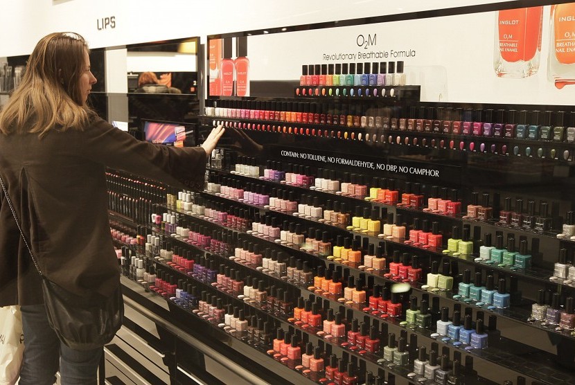 Wanita sedang melihat beragam warna cat kuku.
