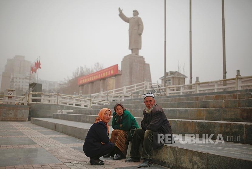 Warg aetnis Uighur dengan latar patung mendiang pemimpin China Mao Zedong di  Khasgar, Daerah Otonomi Xinjiang Uighur, China.