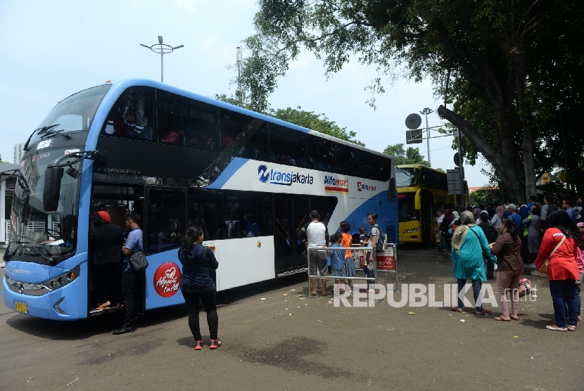 Warga antre untuk naik bus city tour di kawasan Masjid Istiqlal, Jakarta, Senin (26/12)