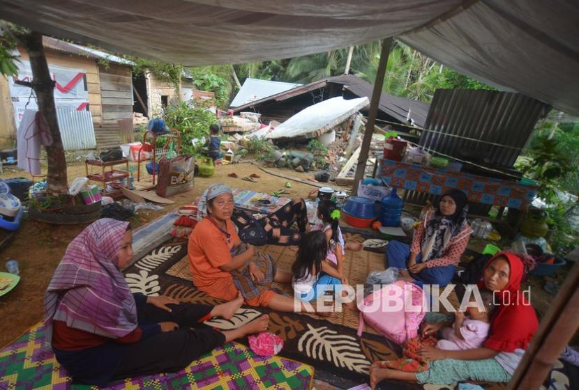 Warga berada di bawah tenda di depan rumahnya yang rusak akibat gempa di Jorong Pinagar, Nagari Aua Kuning, Kabupaten Pasaman Barat, Sumatera Barat, Jumat (25/2/2022). Sekitar 10 ribu pengungsi kini berada di halaman Kantor Bupati Pasaman Barat.