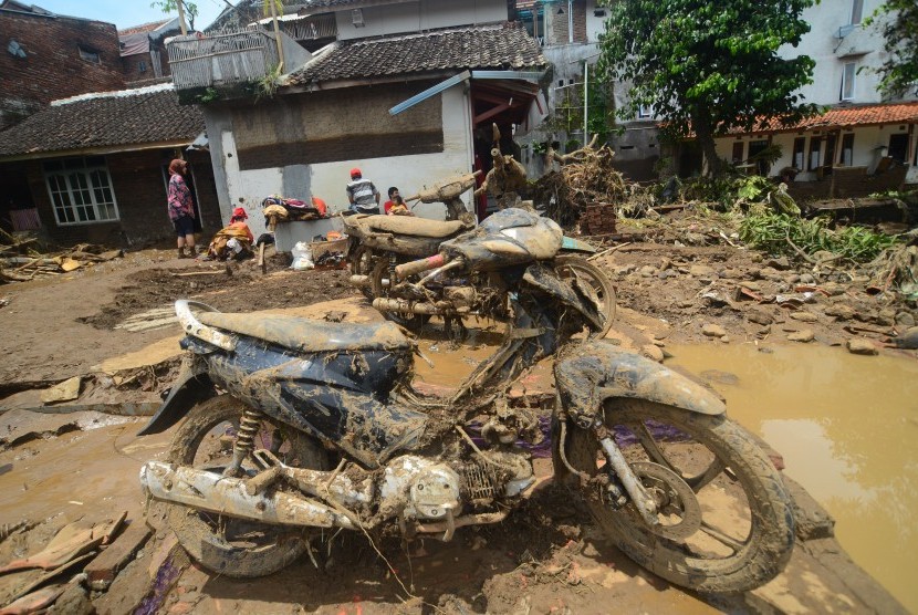 Warga berada di dekat barang-barang yang terselamatkan dari puing bangunan rumah yang roboh akibat diterjang banjir bandang aliran Sungai Ciamanuk di Kampung Cimacan, Kecamatan Tarogong, Kabupaten Garut, Jawa Barat, Rabu (21/9).