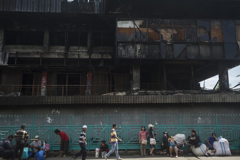 Warga berada di dekat deretan kios yang terbakar di Pasar Senen, Jakarta Pusat, Jumat (20/1). 