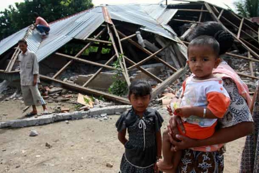  Warga berada di depan puing rumah yang roboh akibat gempa (ilustrasi)