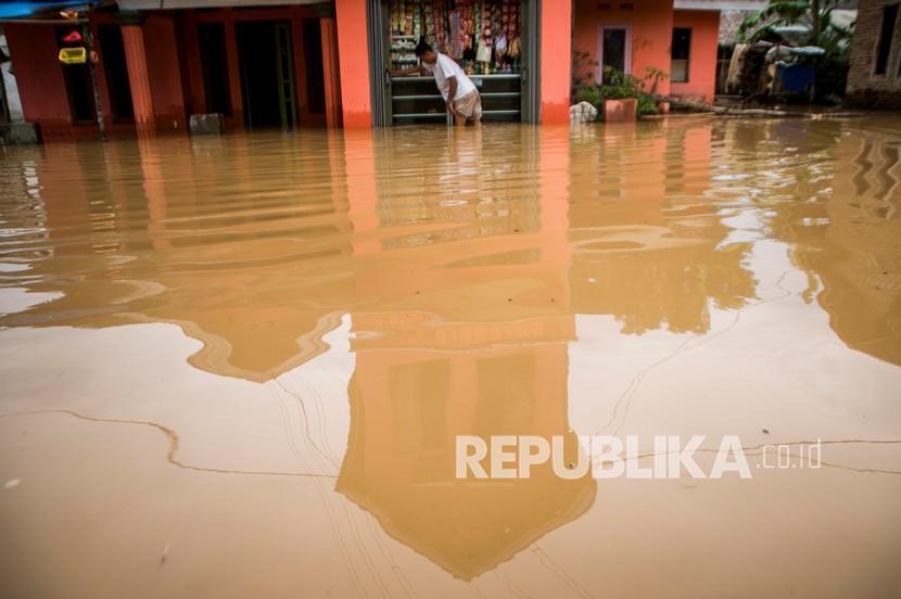 Warga berada di depan rumahnya yang terendam banjir di Desa Keusik, Lebak, Banten, Kamis (3/12/2020). Banjir yang disebabkan meluapnya Sungai Cimoyan akibat curah hujan tinggi sejak malam hari mengakibatkan puluhan rumah di daerah tersebut terendam banjir.
