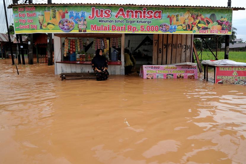 Warga berada di depan rumahnya yang terendam banjir di kawasan Kenali Asam Bawah, Jambi, Selasa (24/5/2022). Sejumlah rumah di beberapa kecamatan di kota itu terendam banjir hingga setinggi paha orang dewasa setelah diguyur hujan lebat selama lebih dari 3 jam. 