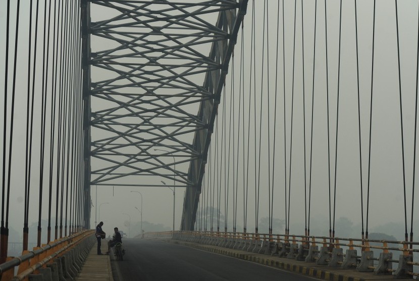 Warga berada di Jembatan Aur Duri II Sungai Batanghari yang tertutup kabut asap di Jambi, Rabu (9/9). 