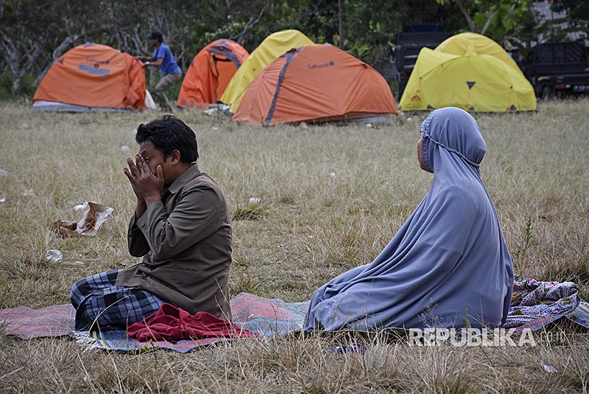 Warga berada di rumahnya yang rubuh akibat gempa di Desa Sembalun Bumbung, Kecamatan Sembalun, Selong, Lombok Timur, NTB, Minggu (29/7). Warga korban gempa melaksanakan sholat Asar di pengungsian di lapangan Desa Sajang, Kecamatan Sembalun, Selong, Lombok Timur, NTB, Minggu (29/7).