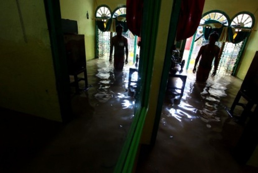 Warga berada di rumahnya yang terendam banjir di kawasan Kampung Rawajati, Jakarta, Senin (16/11).