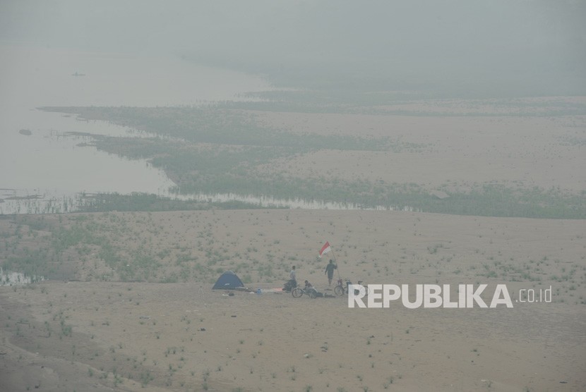 Warga berada di tepi Sungai Batanghari yang diselimuti kabut asap kebakaran hutan dan lahan (karhutla), Jambi