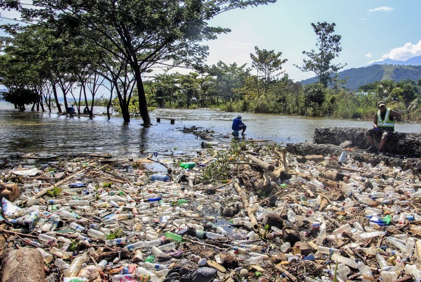 Warga berada diantara sampah yang terbawa akibat meluapnya danau Sentani di Waena Jayapura, Papua.