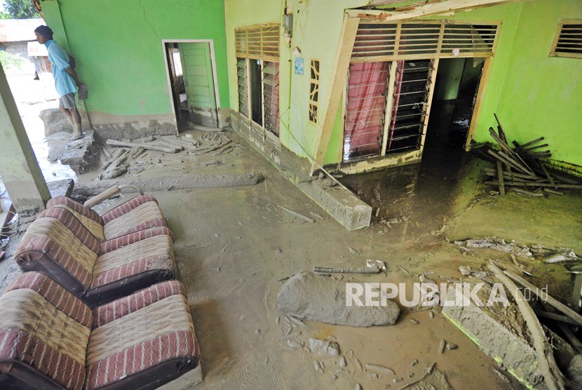 Warga berada disekitar rumahnya yang rusak dan terendam lumpur akibat diterjang banjir bandang (ilustrasi)
