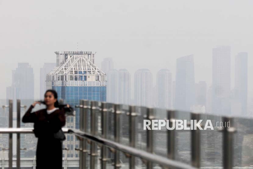 Warga beraktivitas dengan latar belakang gedung bertingkat yang terlihat samar karena polusi udara di Jakarta, Selasa (6/6/2023). Indonesia dinilai perlu membuat sistem peringatan dini polusi.