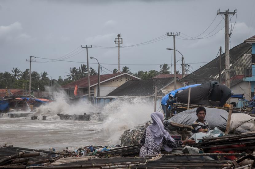 Warga beraktivitas di bibir pantai saat ombak menerjang kawasan tersebut di Teluk Labuan, Pandeglang, Banten.