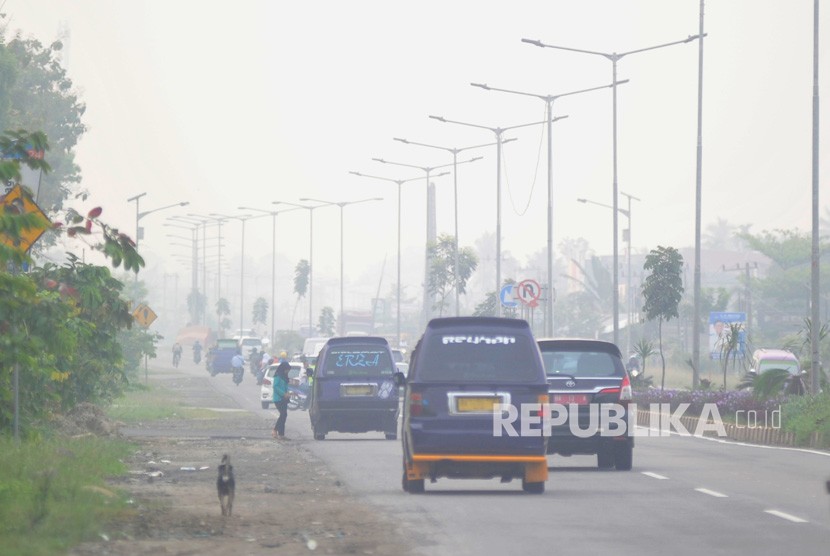 Warga beraktivitas di tengah kabut asap yang menyelimuti kota Padang, Sumatera Barat, Selasa (15/10/2019).
