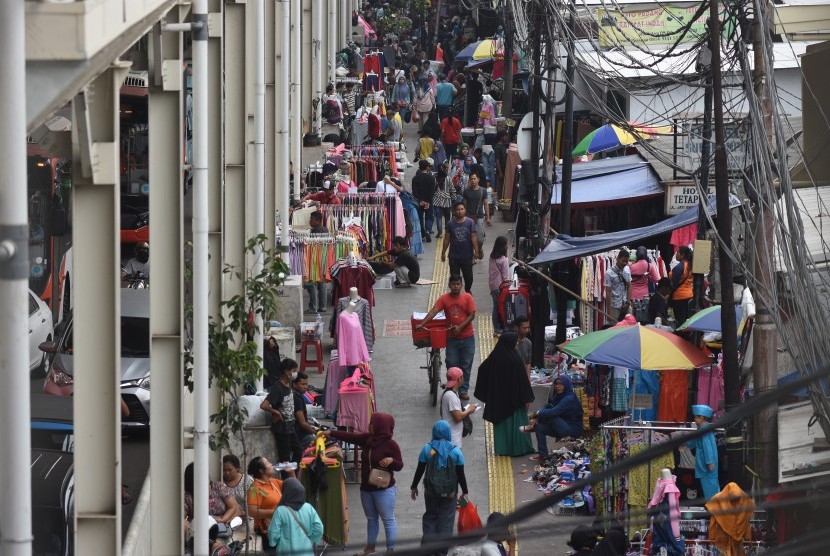 Warga berbagi jalan dengan pedagang kaki lima (PKL) yang berjualan di trotoar jembatan penyebrangan multiguna (skybridge) Tanah Abang, Jakarta, Rabu (15/5/2019). 