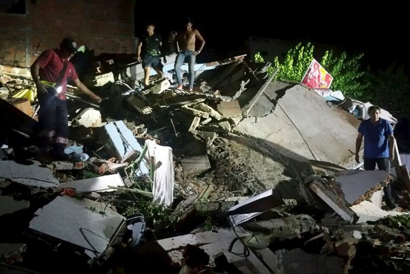Warga berdiri atas runtuhan bangunan akibat gempa bumi berkekuatan 7,8 SR di Manta, Ekuador, Sabtu (16/4).