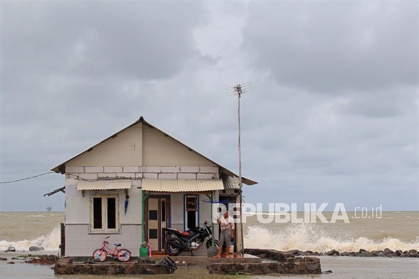 Warga berdiri di depan rumahnya yang terancam abrasi laut di Desa Eretan Kulon, Kecamatan Kandanghaur, Indramayu, Jawa Barat, Rabu (13/1/2021). Sejumlah rumah warga di kawasan itu terancam roboh akibat terkikis abrasi laut dan terhantam gelombang tinggi yang terjadi sejak sepekan terakhir. 