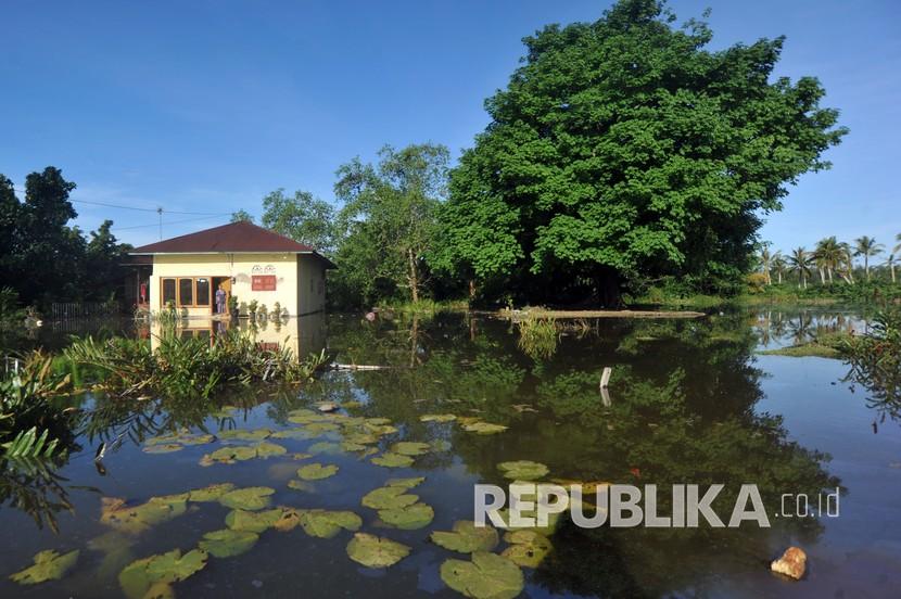 Warga berdiri di depan rumahnya yang terendam banjir rob di Tiram Ulakan, Kabupaten Padangpariaman, Sumatera Barat, Senin (25/5/2020). Banjir rob akibat pasang air laut itu menggenangi kawasan tersebut sejak dua hari terakhir, mengakibatkan sejumlah rumah warga terendam. 