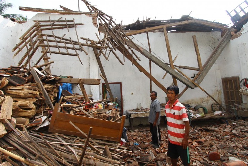 Warga berdiri di depan sebuah rumah yang mengalami kerusakan akibat gempa di Pagelaran, Malang, Jawa Timur, Kamis (17/11). 