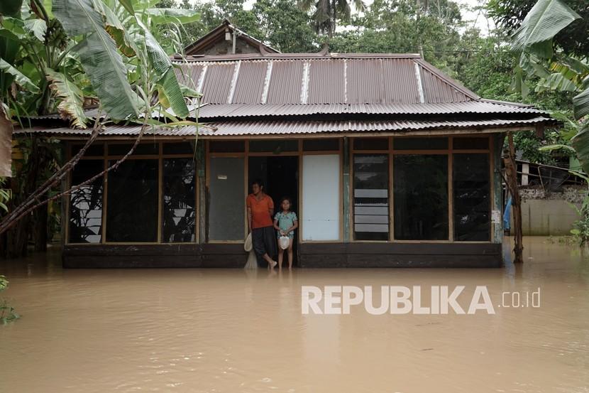 Warga berdiri di pintu rumahnya yang terendam banjir di Desa Gebangsari, Tambak, Banyumas, Jawa Tengah, Selasa (15/3/2022). (Ilustrasi)